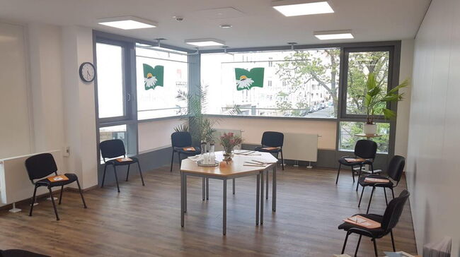 Raum mit Stühlen und Tisch in der Mitte für ein Meeting vorbereitet, große Fenster