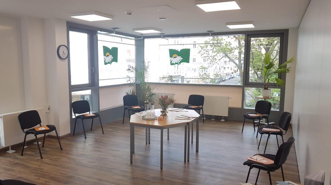 Raum mit Stühlen und Tisch in der Mitte für ein Meeting vorbereitet, große Fenster